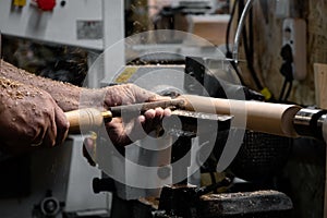 A man in a working apron works on a wood turning lathe.