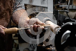 a man in a working apron works on a wood turning lathe.