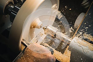 A man in a working apron works on a wood turning lathe