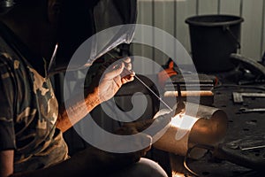 Man working with arc welding machine in garage. Metalwork manufacturing and construction maintenance service. Industrial photo