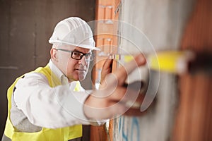 Man Working As Architect Measuring Wall In Construction Site