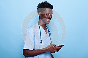 Man working as nurse looking at smartphone and smiling