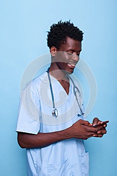 Man working as nurse looking at smartphone and smiling