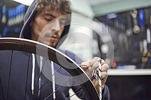 Man working on a bike painting, removing the masking tape of the wheel rim