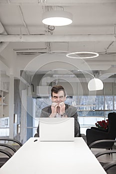 Man working in a bright modern office with a laptop in a business suit