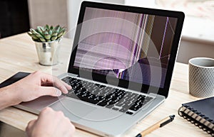 Man working with a broken laptop computer on office business background