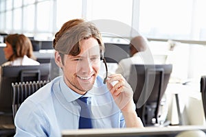 Man working in a call centre,holding headset, close-up