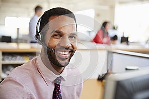 Man working in a call centre smiling to camera, close-up