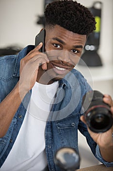 man working on camera lens while making call on smartphone