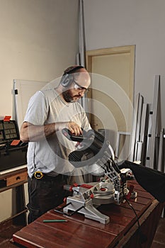 Man working in carpentry with protective accessories. Maneuvering a dangerous electric cutting machine