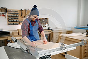 Man working on circular saw and engaged in making wooden blank at workshop