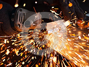 Man is working with a circular saw. Sparks fly from hot metal.
