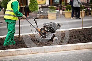 Man working in the city streets with Garden Tiller. Close-up male plow. Cultivator machine.