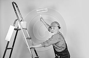 man in working clothes painting wall in empty room. painter in overall and cap with paint bucket. builder worker