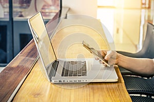 Man working from coffee shop using smart phone and notebook