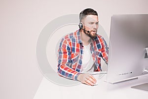 Man working on computer with headset in office at desk