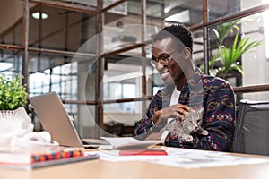 Man working with computer holding a kitten