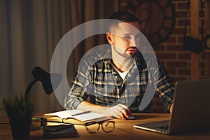 Man working on computer at home at night in dark