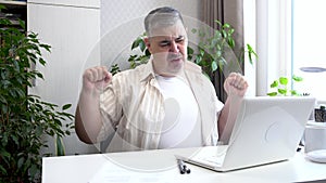 A man working on a computer at home is tired and yawns