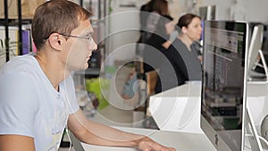 Man is working at a computer in a noisy and crowded office.