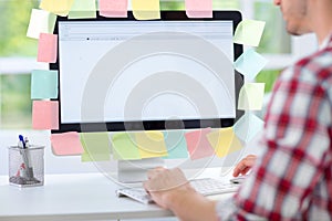 Man working on computer with sticky notes