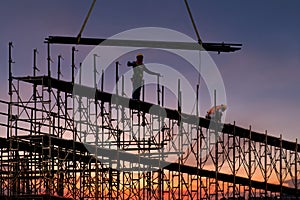 Man working on construction site with scaffold and building with sunset background,scaffolding for construction factory photo