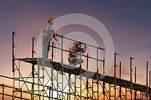 Man working on construction site with scaffold and building with sunset background,scaffolding for construction factory