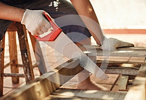 Man working cutting plank with handsaw