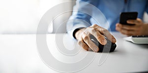 man working with desktop computer and using smart phone in office