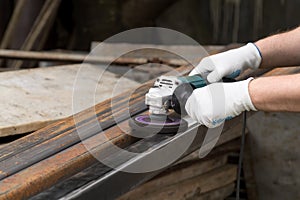 A man working with electric angle grinder tool. Removing rust. Hands in white gloves ho