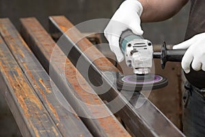 A man working with electric angle grinder tool. Removing rust a metal square tube.