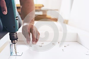 Man is working with furniture assembly using electric screwdriver in new house installation