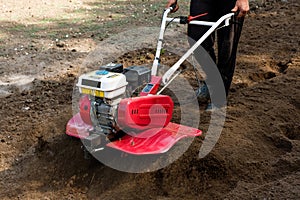 Man working in the garden with garden tiller machine. Garden tiller to work, close up