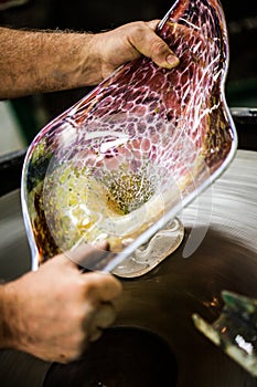 Man Working a Glass Blown Vase on Spinning Silica Sanding Disk photo