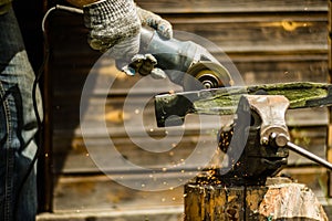 Man working with grinder saw, close up view on tool. Electric saw and hands of worker with sparks. Worker cutting metal