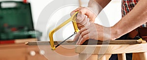 Man working with hand saw indoors, closeup. Banner design