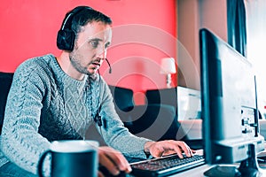 Man working from his couch at home with a computer, headphones.