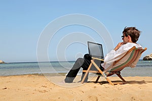 Man working at his pc at the beach