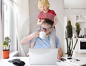 Man working from home with laptop during quarantine. Home office and parenthood at same time. Exhausted parent with hyperactive photo