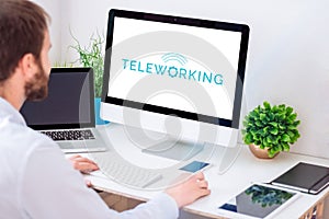 Man working from home using computer with teleworking logo on the screen photo