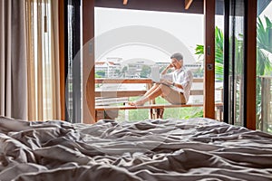 Man working on laptop computer at hotel balcony by the river.