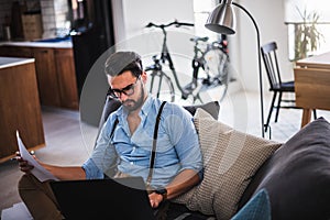 Man working on laptop computer while sitting on sofa