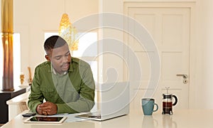 Man working on laptop at dining table in kitchen at comfortable home