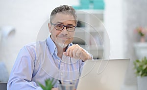 Man working with laptop in home office sitting at desk