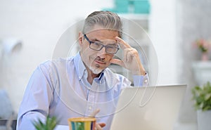 Man working with laptop in home office sitting at desk