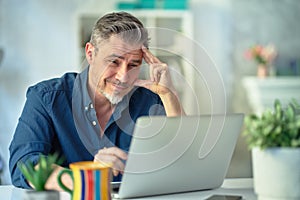 Man working with laptop in home office sitting at desk