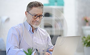 Man working with laptop in home office sitting at desk