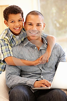 Man working on laptop at home with son