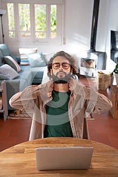 Man working with laptop from home stretching back to correct posture. Overworked Computer Concept.