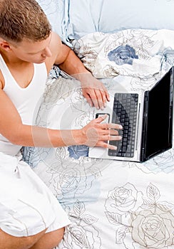 Man working on laptop laying in bed